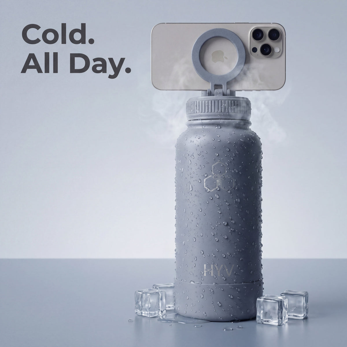Condensation-covered HYV MagFlex bottle holding a phone on its magnetic ring, with ice cubes at its base